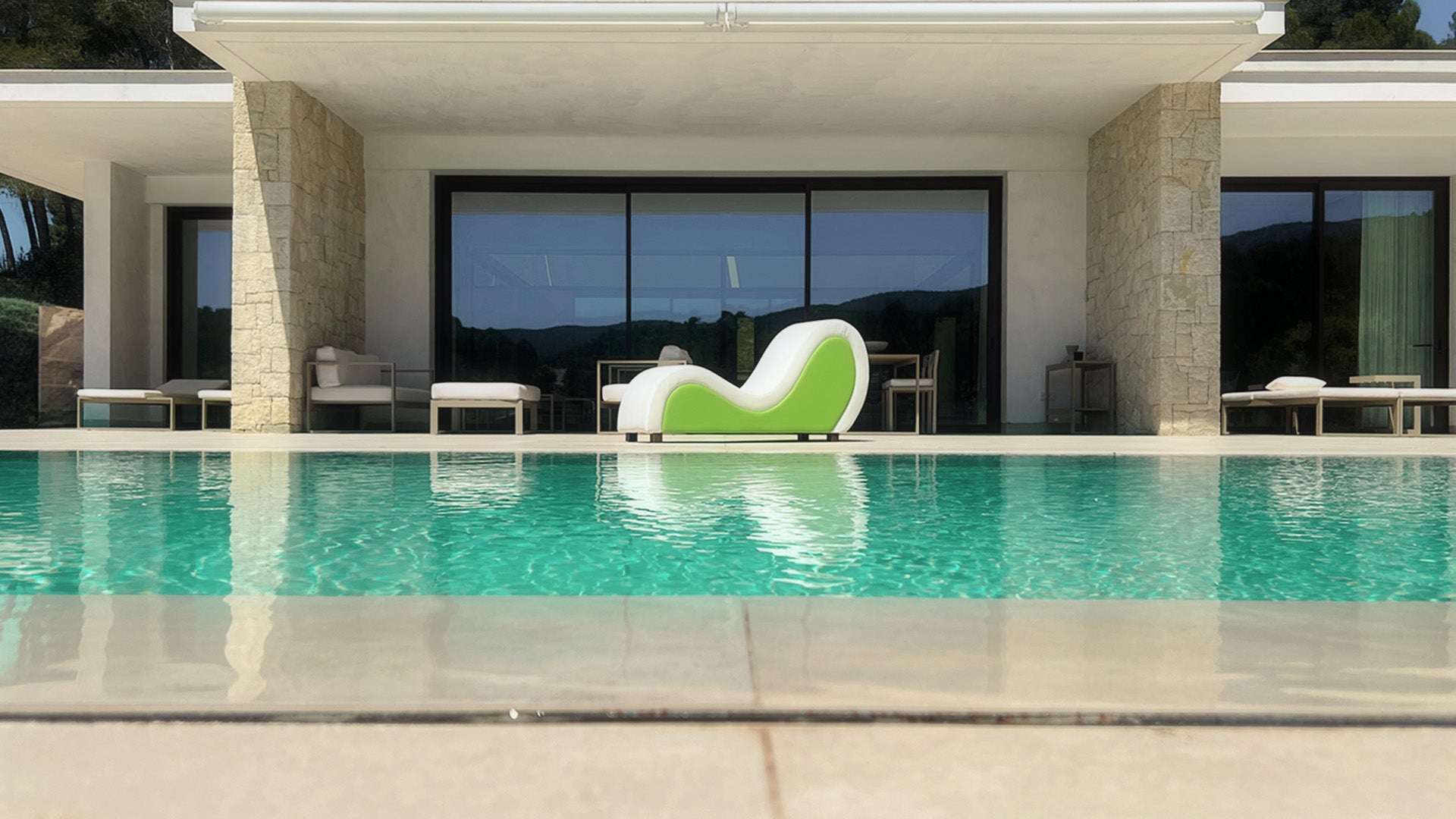 Sofá tántrico, blanco y verde, en la piscina de una casa de lujo